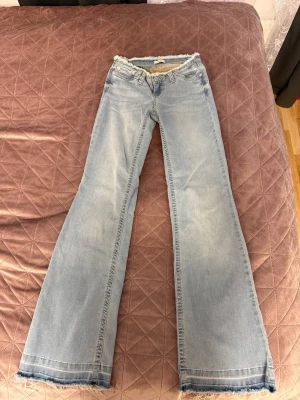 Ljusblå bootcut jeans från Nelly - Säljer ett par ljusblå bootcut jeans med snygga råa kanter i midja och benslut. Jeansen från Nelly, oanvänd 