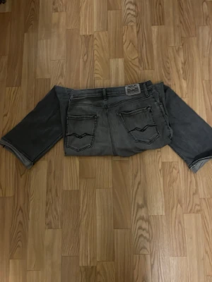 Grå jeans från replay jeans - Säljer ett par grå jeans från replay med raka ben och klassiska bakfickor med vågig söm. Jeansen har en tvättad look och är tillverkade i denim. Perfekta för en avslappnad och trendig stil.