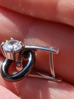 Silverörhänge med stor klar sten - Snyggt örhänge i silverfärgad metall med en stor, rund klar sten i fattning och en cirkelformad detalj undertill. Modern design med blanka ytor som ger ett stilrent intryck. Perfekt för dig som gillar statement-smycken.