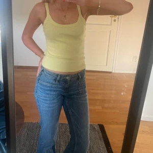 Ljusgul ribbad linnetopp - Snygg ljusgul ribbad linnetopp med breda axelband och rundad halsringning. Toppen sitter tight och är superfin nu till våren och sommaren!