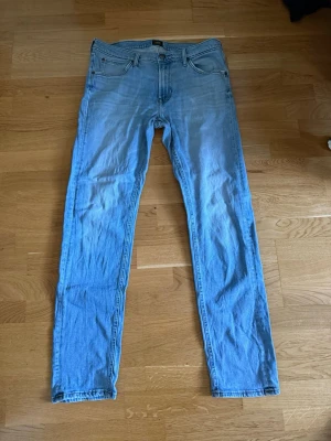 Ljusblå raka jeans från Lee - Säljer ett par ljusblå jeans från Lee med klassisk femficksmodell och raka ben. Jeansen har normal midja och Lee-logga på bakfickan samt patch bak i midjan. Tillverkade i bomull för en skön och avslappnad look.