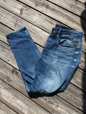 Replay jeans - Snygga blå jeans med raka ben och diskreta slitningar framtill från Replay. Klassisk femficksmodell med dragkedja och knapp. Jeansen har en cool tvättad look och passar perfekt till en avslappnad stil. Materialet är denim i bomull. Storleken är W36 L32