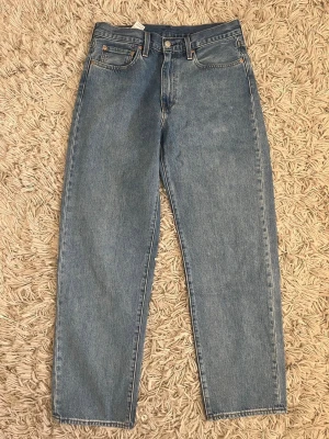 Levi's 568 ljusblå 31/32 - Klassiska blå jeans från Levi's med rak passform och hög midja. Jeansen har fem fickor, knappgylf och är tillverkade i 100% bomull. Perfekta för en avslappnad och tidlös stil. Storlek 31/32