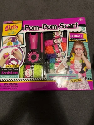 Pom-Pom Scarf pysselkit - Pysselkit för att göra egna pom-pom halsdukar. Innehåller garn i flera färger, verktyg och instruktioner. Perfekt för dig som gillar att skapa egna accessoarer. Färgglada material och enkel att använda.