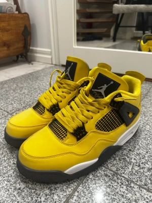 Air Jordan 4 Retro Lightning - Snygga Air Jordan 4 Retro sneakers i en fet gul färg med svarta och vita detaljer. Skorna har klassisk meshpanel, svarta plastdetaljer och Jumpman-logga på plösen. Ovandelen är i läder och sulan är vit med svarta partier. Perfekta för dig som vill sticka ut. Pris kan diskuteras!