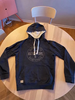 Marinblå hoodie Race Marine - Snygg marinblå hoodie från Race Marine med vit dragsko och tryck på bröstet. Mjuk insida och klassisk känguruficka framtill. Perfekt för en avslappnad stil och enkel att matcha med jeans eller joggers. 