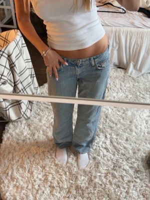 Ljusblå raka jeans med låg midja - Säljer ett par ljusblå jeans med rak passform och låg midja. Jeansen har klassisk femficksdesign och stängs med knapp och dragkedja. Perfekta till en avslappnad och trendig look. Materialet är denim i bomull.