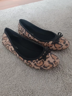 Leopardmönstrade ballerinaskor med rosett - Snygga ballerinaskor med leopardmönster och svarta rosetter, fint skick! 🐆 Storlek 34 men passar förmodligen en något större storlek! 