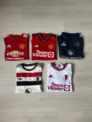 5st Manchester United fotbollströjor  - 5 Manchester United fotbollströjor där dem flesta har namn på ryggen. Alla tröjor är i toppskick utan defekter. Alla är i storlek S förutom tröjan längst upp till vänster, den är 15/16yr men sitter som S. Säljer en tröja för 349 och alla fem för 1199. Skriv vid frågor och kolla gärna in min profil för fler fotbollströjor o annat:)