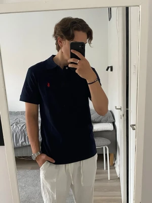Ralph Lauren piké  - Säljer en snygg mörkblå pikétröja från Ralph Lauren i storlek M. Tröjan är använd ett fåtal gånger och är i mycket bra skick – inga fläckar, hål eller andra skador.  Klassisk design med krage, knappar framtill och den ikoniska loggan i rött på bröstet som ger en stilren och tidlös look. Passar lika bra till vardags som till mer uppklädda tillfällen.  Storlek M, passar dig som är cirka 175–185 cm beroende på hur du vill att den ska sitta.  Hör av dig vid intresse!