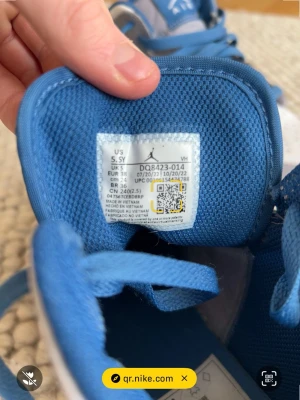 Blue cement Air Jordan 1 Mid sneakers - Snygga Air Jordan 1 Mid sneakers i blått och vitt med klassisk siluett. Skorna har blå mesh och läderdetaljer, samt vita partier på tån och sidorna. Ikonisk Jumpman-logga på plösen och bekväm vadderad insida.
