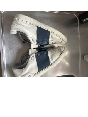 Vita sneakers med blå detalj - Snygga vita sneakers med breda mörkblå paneler på sidorna och matchande blå detaljer på plösen. I ett 6/10 skick men har mycket mer att ge. Kom gärna med byten eller prisförslag☺️👍
