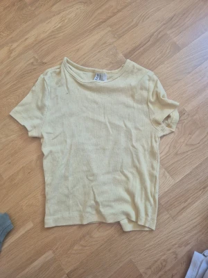 Ljusgul ribbad t-shirt - En ljusgul ribbad t-shirt med korta ärmar och rund hals. T-shirten har en enkel och clean design som passar till det mesta.