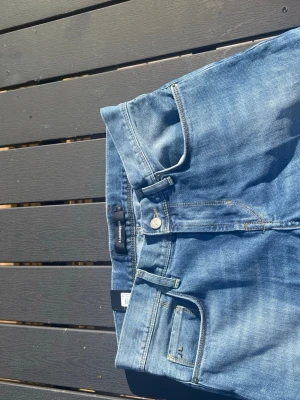 J.Lindeberg jeans - Snygga blå jeans från Lee med klassisk femficksmodell och raka ben. Jeansen har gul kontrastsöm och en liten metallogo på myntfickan. Tillverkade i slitstark denim som passar perfekt till vardagslooken.