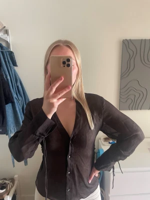 Brun transparent blus - Brun transparent blus med långa ärmar och knappar framtill.