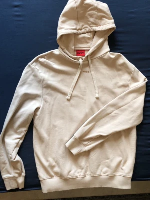 Hugo Boss - Beige hoodie från HUGO med HUGO-logga på bröstet. Perfekt skick, aldrig använd.