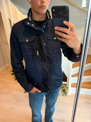 Mörkblå fieldjacket J.Lindeberg - Field jacket från J.Lindeberg  Fint skick utöver lite skador från tvätten - inget man tänker mycket på  XL men passar L