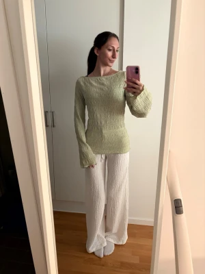 Ljusgrön ribbad långärmad topp - Säljer en ljusgrön långärmad topp med ribbad struktur och lätt utsvängda ärmar. Toppen har en kroppsnära passform och är perfekt för dig som gillar en enkel men trendig stil. Materialet känns mjukt och stretchigt, vilket gör den bekväm att bära.