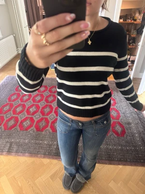 Svartvit randig stickad tröja från GAP - Säljer en svart stickad tröja med vita horisontella ränder. Tröjan har en croppad passform, rund halsringning och ribbade muddar vid ärmslut och nederkant. Perfekt till jeans för en avslappnad look.