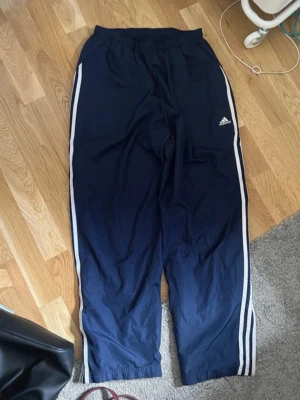 Vintage adidas trackpants gym byxor - köpta på second hand, blir wide leg om man öppnar dragkedjan längst ner men man kan även stänga den, använda men fortfarande bra vintage skick, sönder vid ena dragkedjan (se bild) men påverkar inte hur den fungerar och syns inte på! finns ingen lapp men hade sagt storlek S/XS, man kan spänna/lossna de i midjan