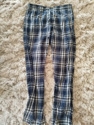 Rutiga pyjamasbyxor  - Mysiga pyjamasbyxor från 157 i blått och vitt rutigt mönster. Byxorna har resår i midjan och är tillverkade i mjukt tyg, perfekta för chillkvällar hemma. Klassisk rak passform och skön känsla.
