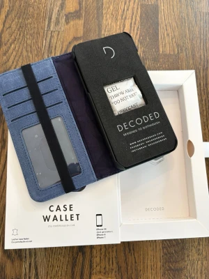 Blått fodral från Decoded till iPhone 7/8/SE - Snyggt blått mobilfodral från Decoded, passar iPhone 7, 8 och SE. Fodralet har flera kortfack, fönster för ID och elastiskt band för extra säkerhet. Perfekt för dig som vill ha både skydd och stil på mobilen.