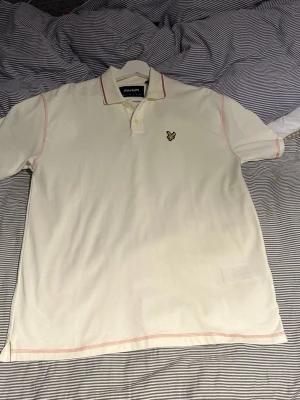 Vit piké från Lyle & Scott - Klassisk vit pikétröja från Lyle & Scott med gul logga på bröstet och röda sömmar längs kanterna. Tröjan har krage, knappar vid halsen och korta ärmar. Perfekt för en clean och stilren look. Helt oanvänd då jag fick den för två år sen i XS och tänkte att den skulle passa men var alldeles för stor. Vi skulle då vänta tills jag blev äldre men den är nästan som om den vore XL, jag är själv 176 och den är alldeles för stor. Rekommenderar till folk som är 185 +