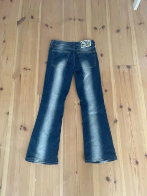 Blå bootcut kvarg jeans - Säljer ett par blå bootcut jeans med en vit slitning/rand på bågade fram och baksidan på byxbenen, eller så kan man kalla det kvargjeans.