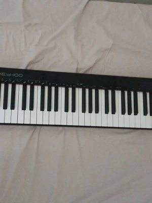 VisionKEY-100 digitalt keyboard - Säljer ett VisionKEY-100 digitalt keyboard med svart plastchassi och vita samt svarta tangenter. Keyboardet har flera kontrollknappar, en liten display och klassisk rektangulär form. Perfekt för dig som vill spela eller producera musik hemma.