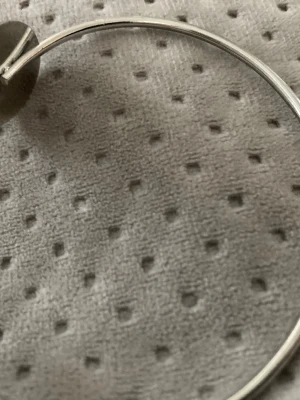 Silvrigt öppet armband med plattor - Snyggt och minimalistiskt armband i silverfärgad metall. Armbandet är öppet och har två runda, platta ändar som ger en modern och stilren look. Perfekt för dig som gillar enkel men trendig design.