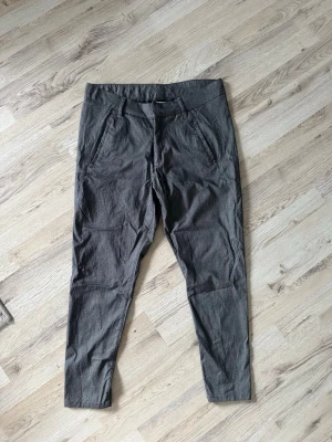 Mörkgrå chinos med raka ben - Snygga mörkgrå chinos med raka ben och klassiska sidfickor. Byxorna har hällor för skärp och är tillverkade i ett mjukt, vävt material som känns bekvämt hela dagen. Perfekta för en stilren och avslappnad look.