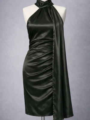 Svart halterneck klänning i satin - Stilren svart halterneck klänning i glansigt satinmaterial. Klänningen har en asymmetrisk scarfdetalj vid halsen och är figurnära med en kort längd. Perfekt för dig som vill ha en elegant och trendig look. Är i storlek XS men funkar även till XXS. Har vaddering vid brösten.  Är köpt från en hemsida som inte finns kvar längre. Nypris: 1299kr