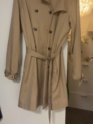 Beige trenchcoat med bälte XL- ny  - Super fin beige ny sommarkappa från vila. Storlek XL- helt oanvänd. Nypris 799kr 