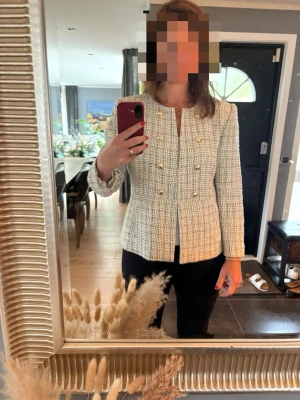 Vit bouclé kavaj med guldknappar Zara - Stilren vit bouclé kavaj med rund halsringning och dekorativa guldknappar framtill. Rak passform och långa ärmar ger en klassisk look. Perfekt att matcha med både jeans och kjol för en trendig outfit.