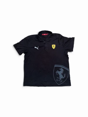 Svart Ferrari x Puma piké - Svart pikétröja från Puma i samarbete med Ferrari. Tröjan har klassisk krage, korta ärmar och stora Ferrari-loggor på bröstet och nedtill. Tillverkad i bomull och har en liten italiensk flagga i nacken. Perfekt för dig som gillar sportig stil och bilar.