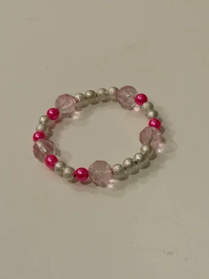 Armband med rosa och silverfärgade pärlor - Handgjort armband med stora ljusrosa, facetterade pärlor, glittriga silverfärgade pärlor och mörkare rosa pärlor. Armbandet är elastiskt och passar de flesta handleder.
