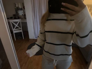 Vit stickad tröja med svarta ränder - Säljer en beige stickad tröja med breda svarta horisontella ränder. Tröjan har rund halsringning o långa ärmar. En liten defekt på sista bilden men det är nog bara att dra in trådarna från insidan , den var så när jag köpte den i butik.använt denna 2 gånger