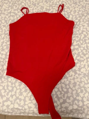 Röd body med smala axelband BikBok - Snygg röd body från BikBok med smala axelband som är skjusterbara . Tillverkad i ett stretchigt material som sitter bekvämt mot kroppen.