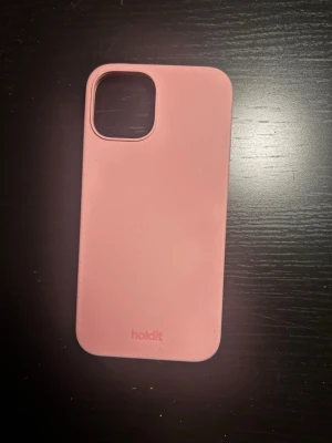 Rosa mobilskal från Holdit - Snyggt rosa mobilskal från Holdit med stilren design och matt finish. Skalets material känns mjukt och greppvänligt, perfekt för dig som vill ha ett enkelt men trendigt skydd till din mobil. Passar modeller med större kameralins. STORLEK: 7cm bred och 14,5 cm lång. Passar iphone 12