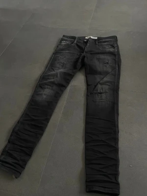 Replay jeans med slitningar  - Tjena!! Säljer ett par riktigt fräscha replay jeans med sjuka slitningar, jeansen är i svart färg slitningar fast inte slitningar så att man ser huden under!! Läder detaljer vid gylfen och lappen på baksidan, W30 L32. Ny pris är 1900 mitt pris är 549! Priset är inte hugget i sten!!! 🪨 