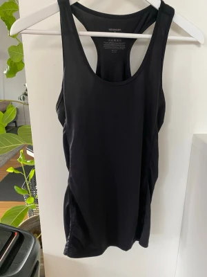 Svart träningslinne från Newbody! Oanvänt!  - Säljer en svart, ärmlös träningstopp från Newbody. Linnet har brottarrygg och är gjort i ett stretchigt syntetmaterial som andas, perfekt för intensiva träningspass. Enkel och stilren design utan mönster eller detaljer.