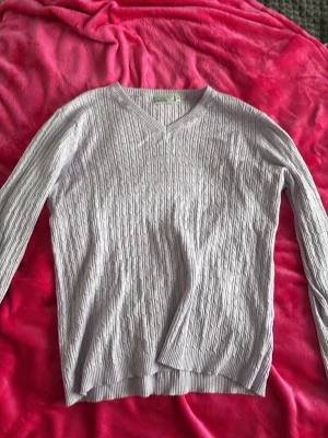 Ljuslila kabelstickad tröja  - Säljer en ljuslila kabelstickad tröja från Isolde med v-ringning och långa ärmar.Tröjan har ribbade muddar vid ärmslut och nederkant, perfekt för lager på lager. Snygg och enkel att matcha till olika outfits. Använt ungefär 5 gånger men inget som tyder på det! Säljer pågrund av aldrig använder längre’