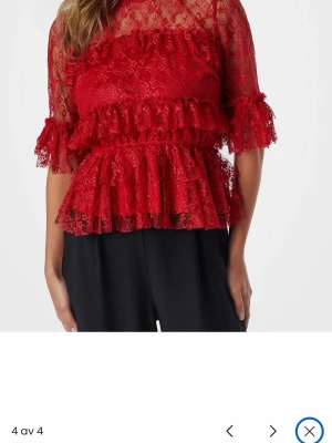 Röd spetsblus med volanger - Prislapp kvar. Trendig röd blus i spets med volangdetaljer och halvtransparenta partier. Blusen har trekvartsärm och en feminin, något utsvängd passform. Perfekt för dig som vill sticka ut med en romantisk look. 
