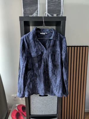 Mörkblå randig skjorta med knappar - Snygg mörkblå skjorta med diskret randigt mönster och knappar framtill. Skjortan har två bröstfickor och långa ärmar. Perfekt för dig som gillar en avslappnad men ändå stilren look.