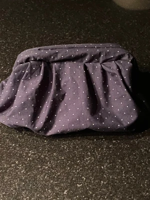 Mörkblå prickig clutchbag  - Söt mörkblå clutchbag i tyg med små vita prickar.