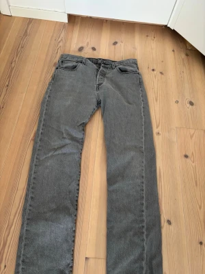 Grå raka jeans från Levi's - Snygga grå jeans från Levi's med rak passform och klassisk femficksdesign. Jeansen har en diskret tvätt och är tillverkade i ett slitstarkt denimtyg. Perfekta för en avslappnad och trendig look.