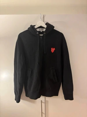 Svart Comme des Garçons Play Hoodie - Tjenare! Säljer en Svart hoodie från Comme des garçons. Säljer tyvärr denna tröjan som gett mig som mest komplimanger. Tröjan har lite mer lösare passform men sitter riktigt snyggt på. Perfekt för en hostigare dag och det kallare väder som ska komma! Vid frågor och funderingar är det bara att skriva! (OBS CDG Play sitter inte tts, dvs denna tröjan sitter mer som en M)