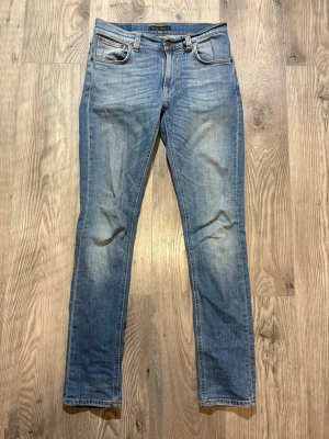 Nudie Jeans - Snygga blå slim fit jeans från Nudie Jeans med klassisk femficksmodell och slitna detaljer på låren. Jeansen har normal midja, dragkedjegylf och är tillverkade i bomull med lite stretch för skön passform.