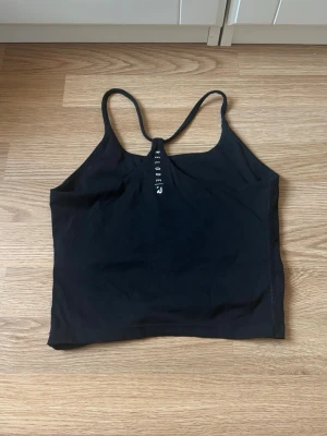 Svart linne Relode - Snygg svart linne från Relode med tunna axelband. Tillverkad i stretchigt material som passar perfekt för träning eller gym. Enkel och stilren look🤍