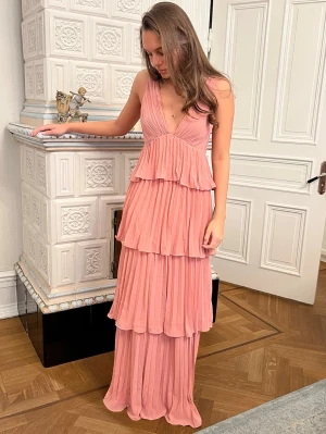 Rosa volangklänning med djup rygg - Säljer en jättefin lång klänning, perfekt till bal eller andra fina tillfällen! Klänning är köpt förra året, men aldrig använd. Prislapp sitter kvar. Klänningen är från hemsidan ”lulus”. Nypris 1550kr.  💕